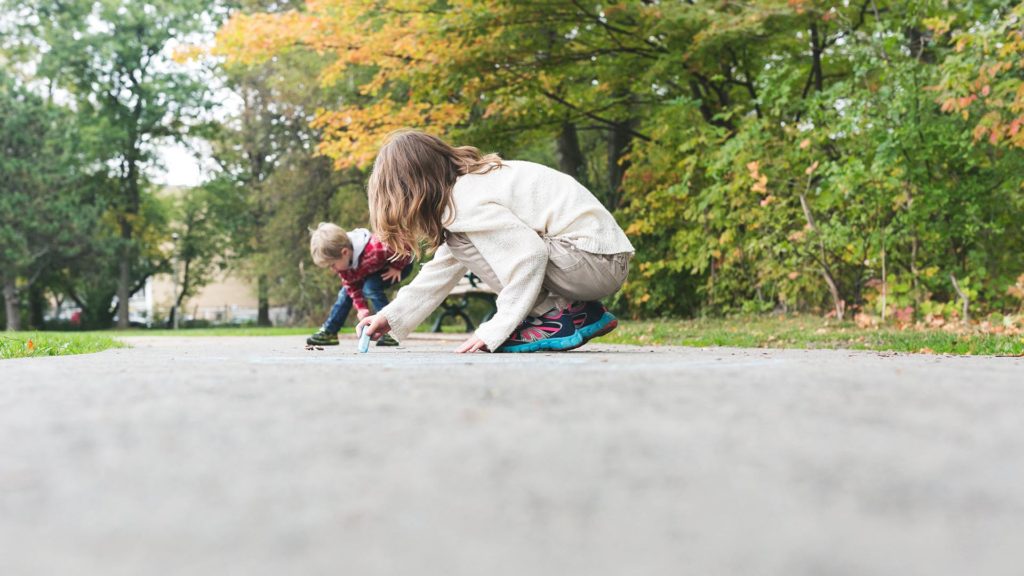 two children drawing with chalk on a sidewalk